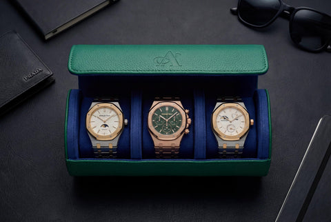 Three watches in a green and blue display case on a dark surface.